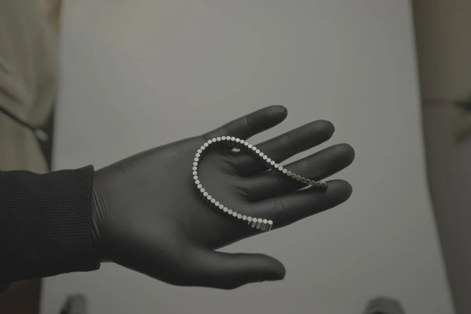A gloved hand holding the bracelet as a curved chain